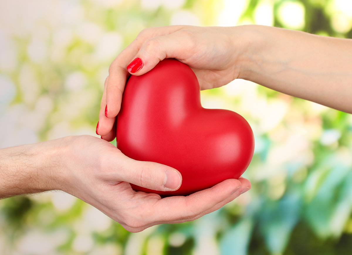 Red,Heart,In,Woman,And,Man,Hands,,On,Green,Background
